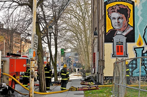     A photo of the Germantown YWCA building during the fire incident. The building is surrounded by emergency vehicles as firefighters are actively working to extinguish the flames.