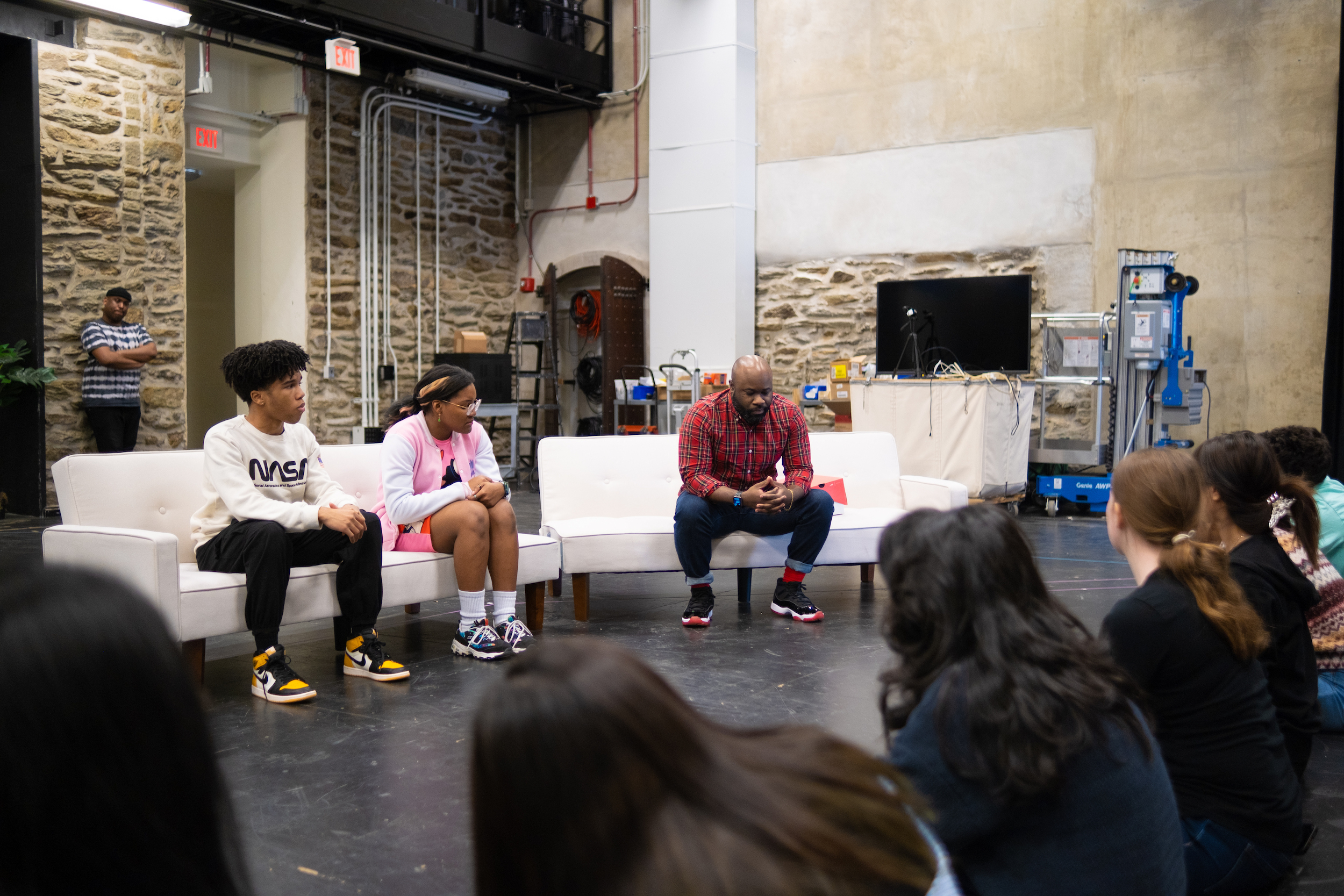 Three actors seated on a sectional sofa.