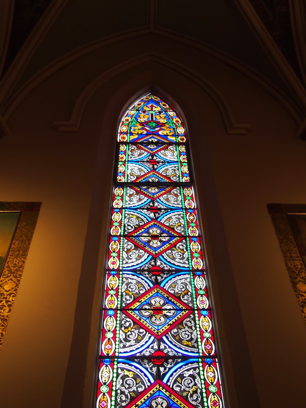Tall stained glass window inside of a church