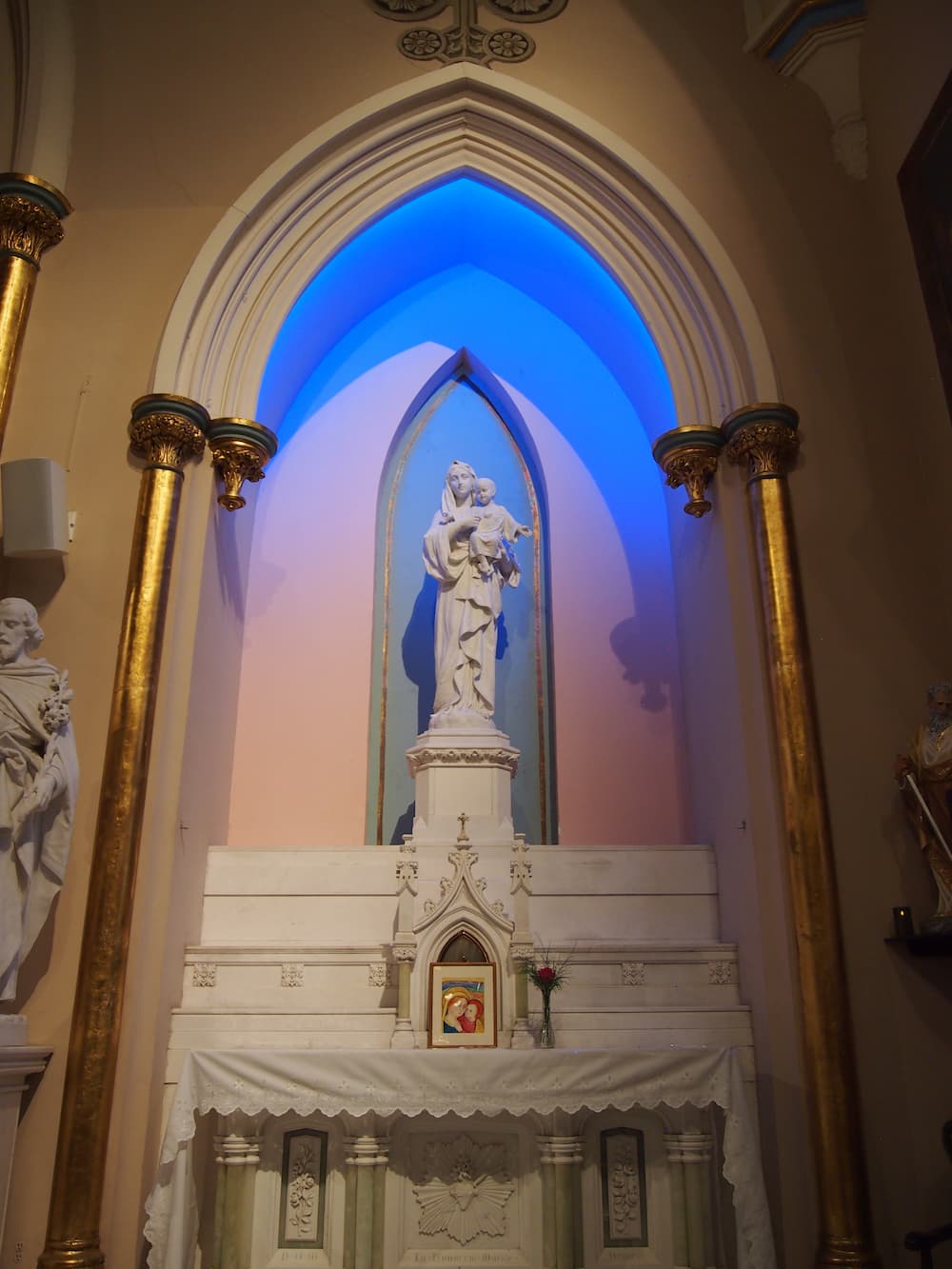 Statue of Mary and baby Jesus inside of a church with blue lighting
