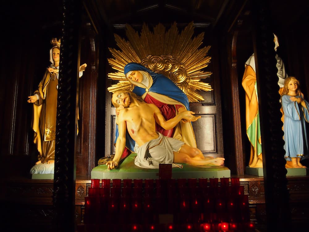 A sculpture scene with votive candles in front