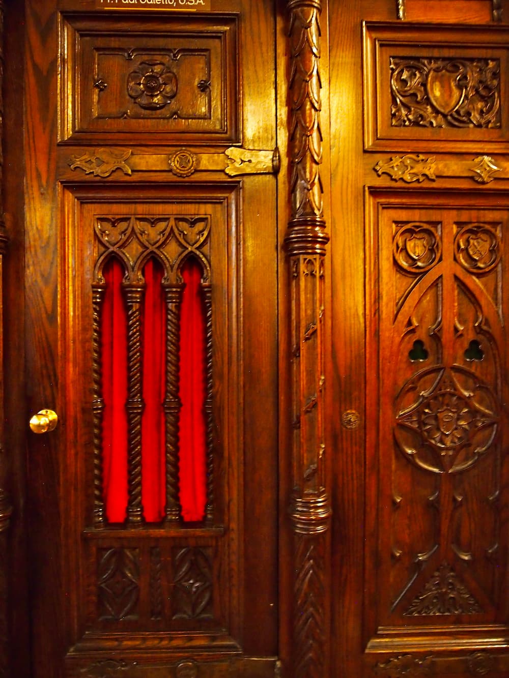 A wooden confessional booth door with ornate decorations
