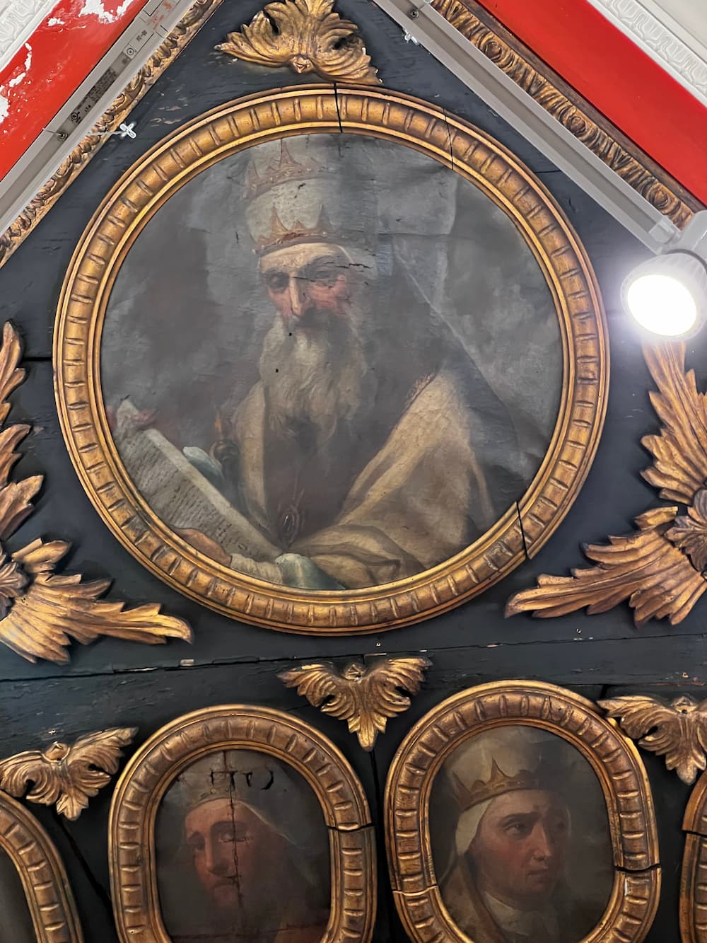 Ornate circle gold frame with a pope in papal tiara painted on the wall