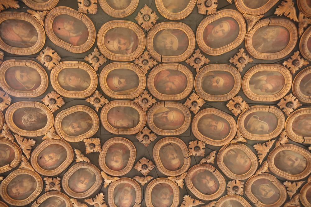 Arrangement of portraits of Popes in ornate gold frames on the ceiling