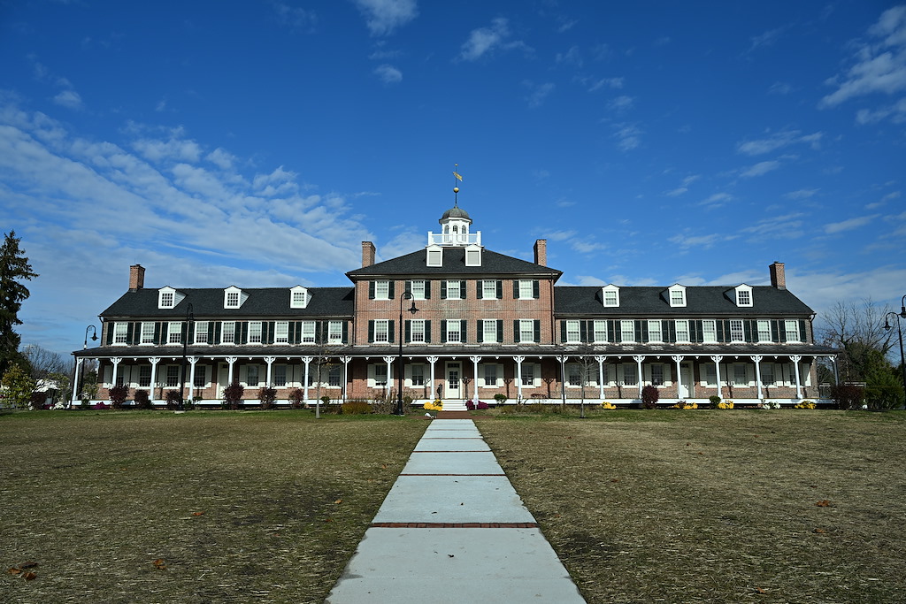 A large historic brick building with many windows and a black roof.
